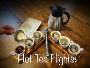 Hot Tea Flights at Loco Espress shown on a flight board with 6 cups of tea and one having cream poured into it.